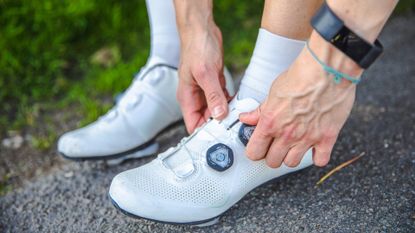 Female cyclist putting on a pair of the best cycling shoes.